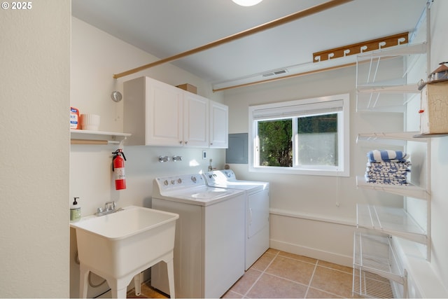 laundry area featuring separate washer and dryer, sink, light tile patterned floors, and cabinets