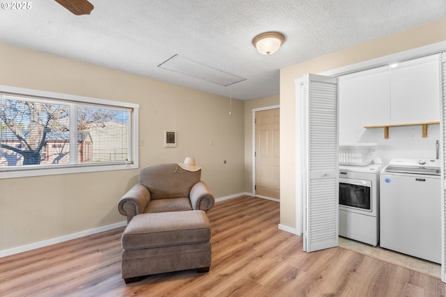 laundry area with light wood-type flooring, a textured ceiling, and washer and clothes dryer