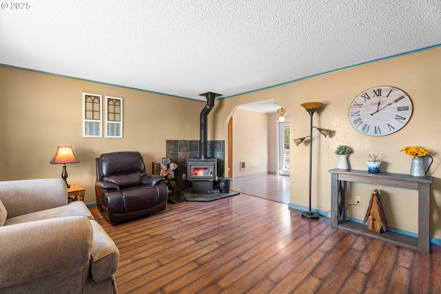 living room featuring dark hardwood / wood-style flooring, a textured ceiling, and a wood stove