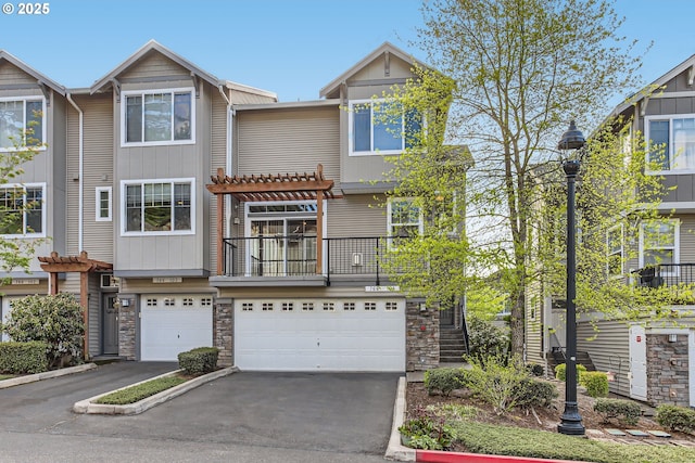 view of property with an attached garage, a pergola, driveway, and stone siding