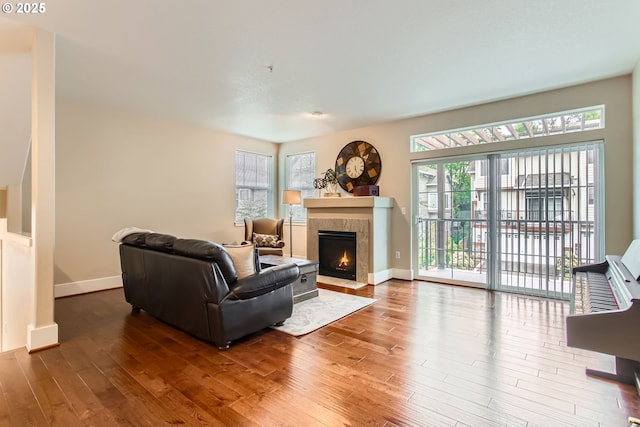 living room with a fireplace with flush hearth, baseboards, and wood finished floors