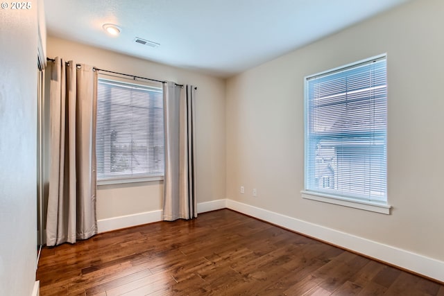 empty room featuring baseboards, visible vents, and dark wood finished floors