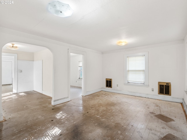 unfurnished living room featuring wood-type flooring and heating unit