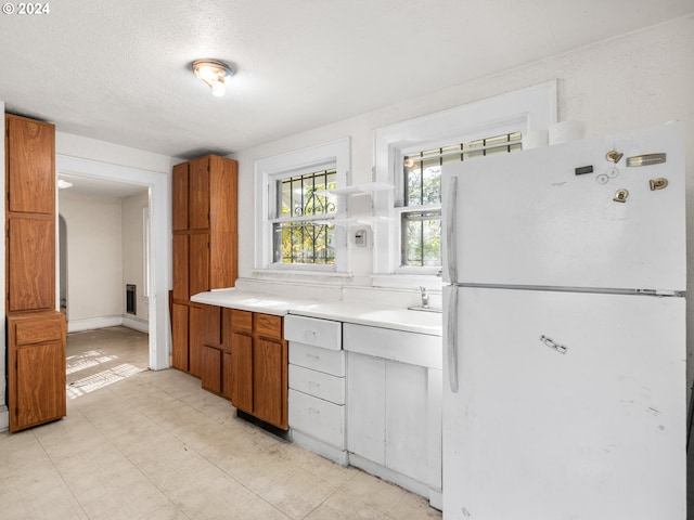 kitchen with sink, white fridge, and a textured ceiling