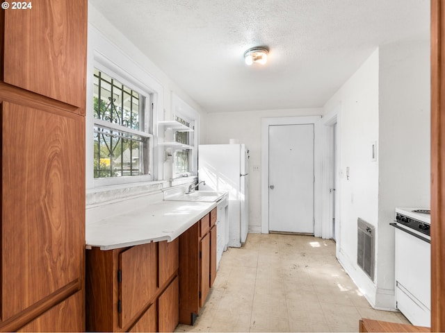 kitchen featuring sink, white appliances, and a textured ceiling