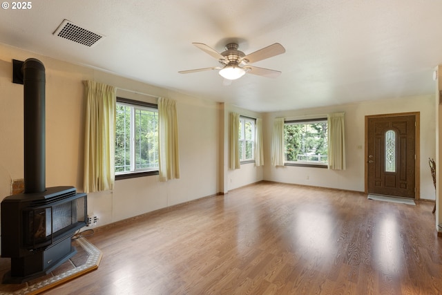 939 Buckhorn Rd, Roseburg, OR 97470 - unfurnished living room with baseboards, a wood stove, visible vents, ceiling fan, and wood finished floors