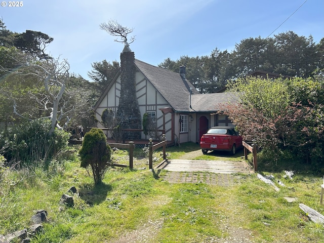 view of front of property featuring a shingled roof, stucco siding, and dirt driveway