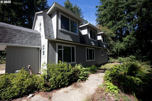 exterior space with a gambrel roof and roof with shingles