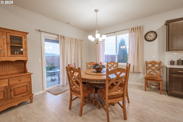 dining area with light wood finished floors, a chandelier, plenty of natural light, and baseboards