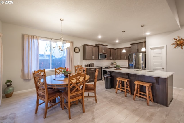 dining room featuring a chandelier, baseboards, light wood-style flooring, and recessed lighting