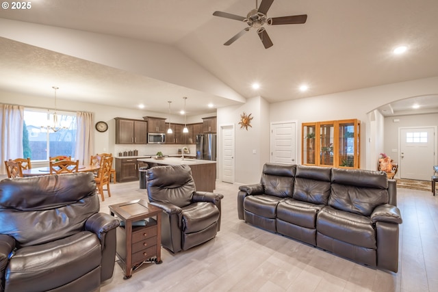 living area featuring arched walkways, lofted ceiling, a ceiling fan, light wood finished floors, and healthy amount of natural light