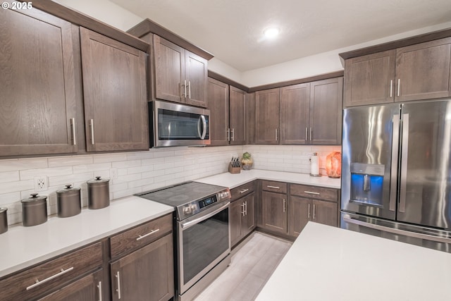 kitchen with appliances with stainless steel finishes, light countertops, light wood-style floors, tasteful backsplash, and dark brown cabinetry