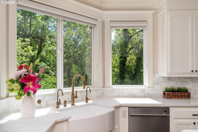 kitchen featuring dishwashing machine, a sink, backsplash, white cabinetry, and light stone counters