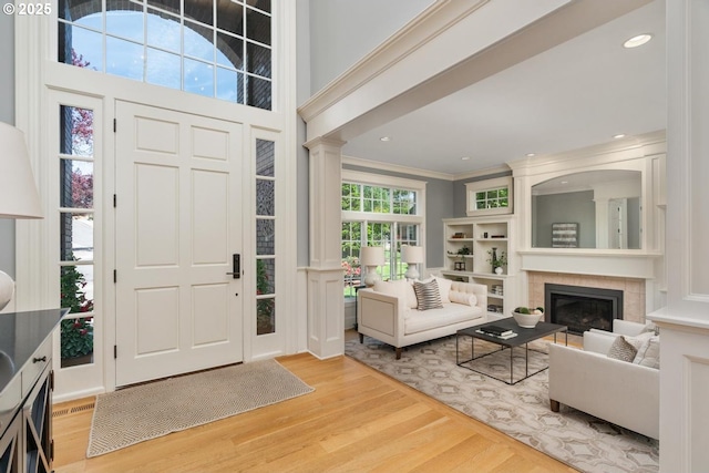 foyer featuring wood finished floors, a large fireplace, and crown molding