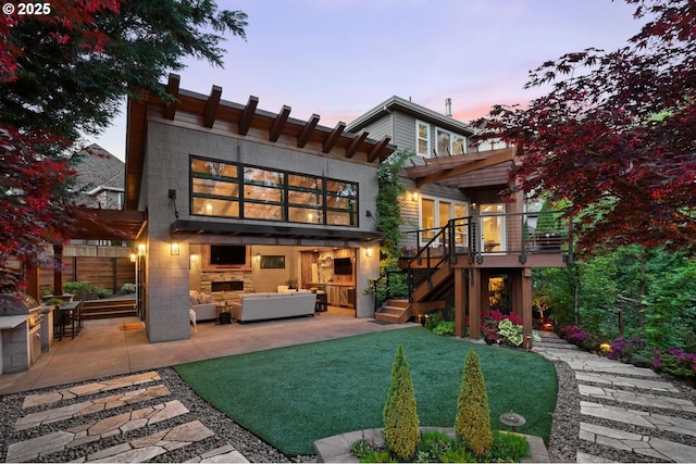 rear view of property with outdoor lounge area, stairs, a patio area, a wooden deck, and a yard