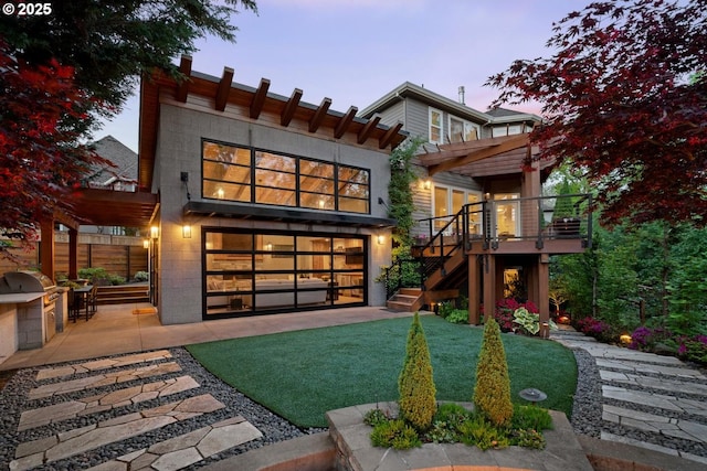 back of property at dusk with area for grilling, stairs, a deck, a patio, and a garage