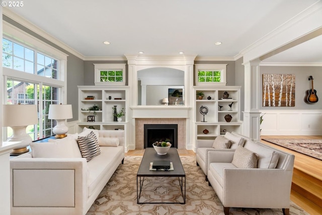 living room featuring healthy amount of natural light, crown molding, a fireplace, and light wood-style flooring