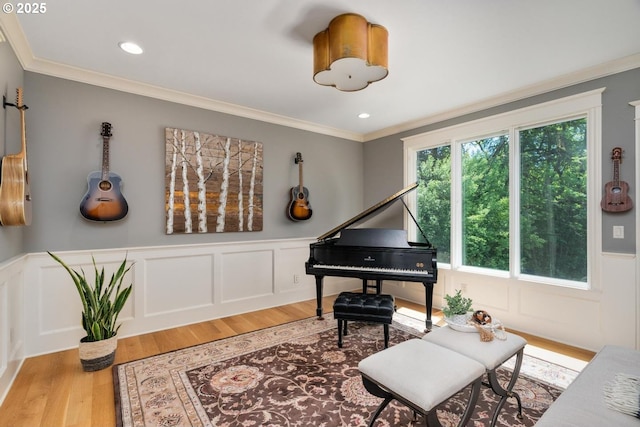 sitting room featuring light wood-style flooring, a wainscoted wall, crown molding, a decorative wall, and recessed lighting