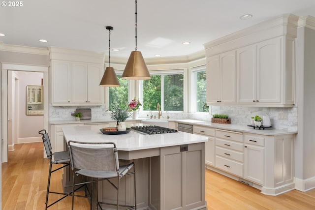 kitchen with light countertops, light wood finished floors, tasteful backsplash, white cabinets, and ornamental molding