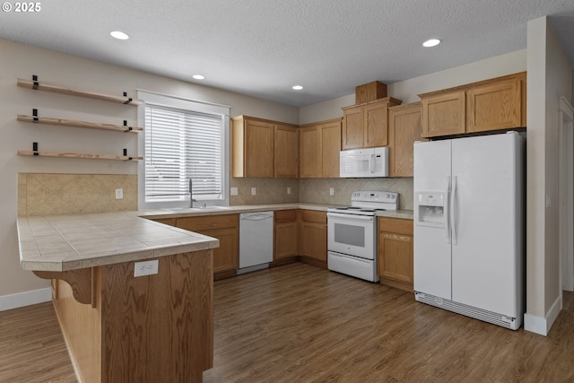 705 NW 25th Ave, Battle Ground, WA 98604 - kitchen featuring white appliances, a sink, a peninsula, wood finished floors, and a kitchen bar