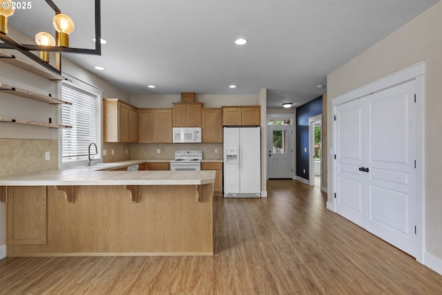 705 NW 25th Ave, Battle Ground, WA 98604 - kitchen featuring white appliances, tile countertops, light wood-type flooring, a peninsula, and a textured ceiling
