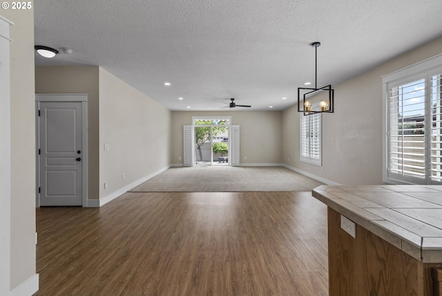 705 NW 25th Ave, Battle Ground, WA 98604 - unfurnished dining area featuring dark wood finished floors, baseboards, a ceiling fan, a textured ceiling, and a chandelier