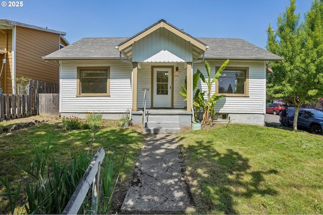 bungalow-style house featuring fence, roof with shingles, board and batten siding, and a front lawn
