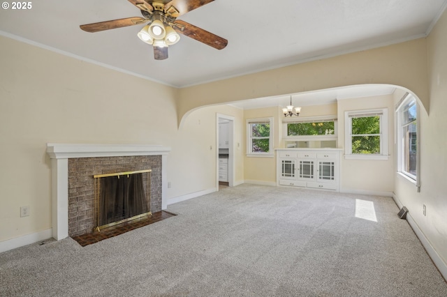 unfurnished living room featuring a brick fireplace, baseboards, arched walkways, carpet flooring, and ceiling fan with notable chandelier