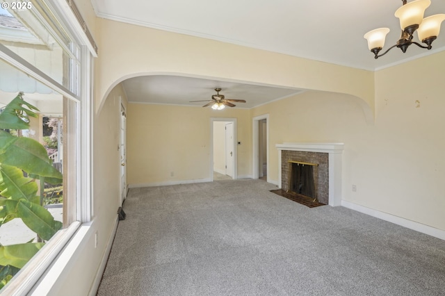 unfurnished living room with arched walkways, a wealth of natural light, a fireplace, and carpet flooring