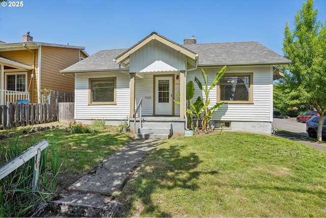 bungalow-style house featuring roof with shingles, fence, a chimney, and a front yard