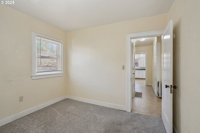 carpeted spare room featuring baseboards