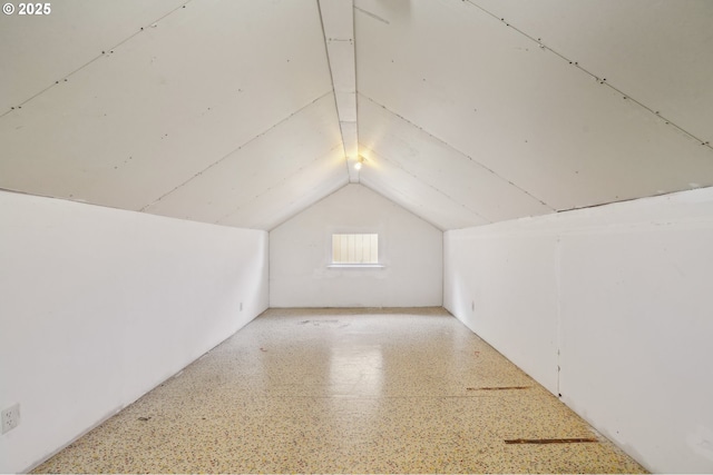 bonus room with speckled floor and lofted ceiling