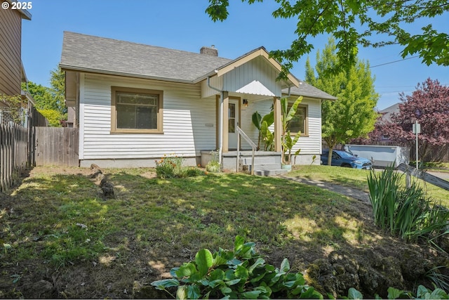 bungalow-style house featuring fence, a chimney, roof with shingles, and a front yard