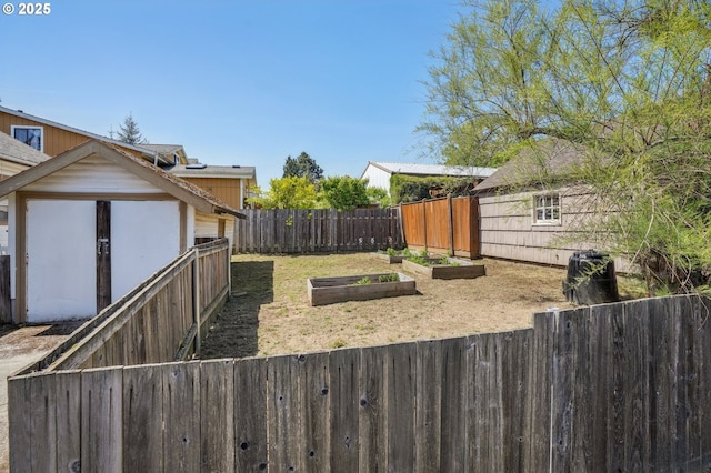 view of yard featuring a fenced backyard, a shed, an outbuilding, and a vegetable garden