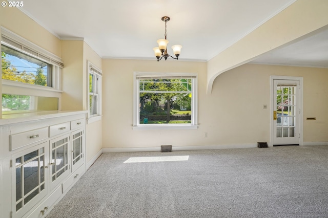 carpeted empty room featuring baseboards, a chandelier, and a healthy amount of sunlight
