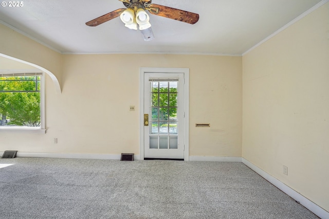 carpeted spare room featuring crown molding, baseboards, a ceiling fan, and visible vents