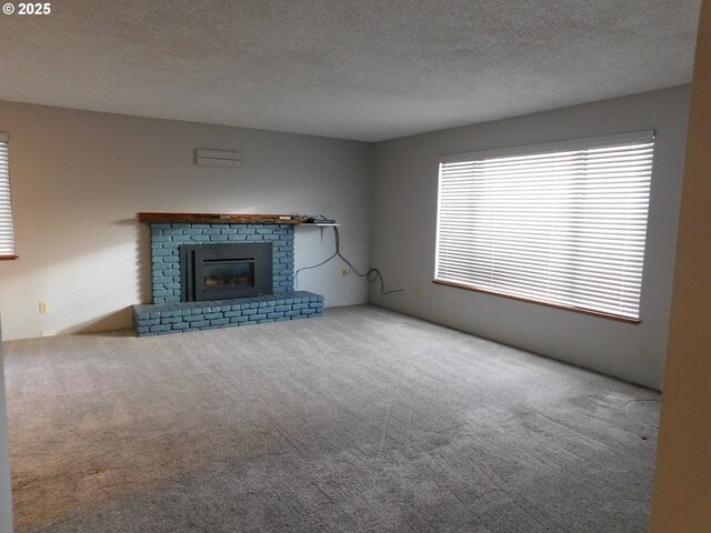 unfurnished living room with carpet floors, a fireplace, and a textured ceiling