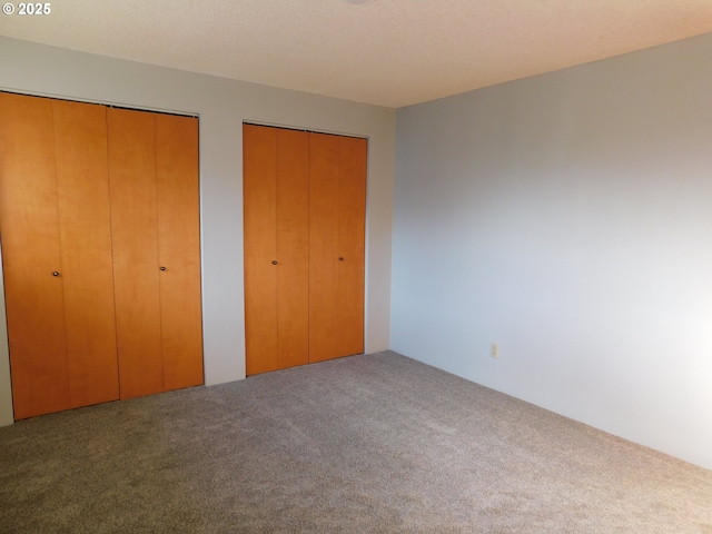 unfurnished bedroom featuring carpet floors and multiple closets