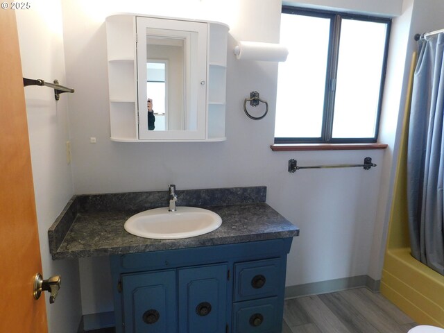 bathroom featuring hardwood / wood-style flooring, shower / bath combo, and vanity