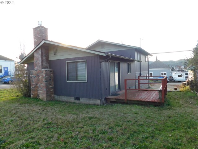 rear view of house featuring a wooden deck and a lawn