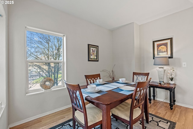 dining space featuring light wood-type flooring and baseboards