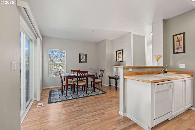 kitchen featuring a sink, dishwasher, white cabinets, and light wood finished floors