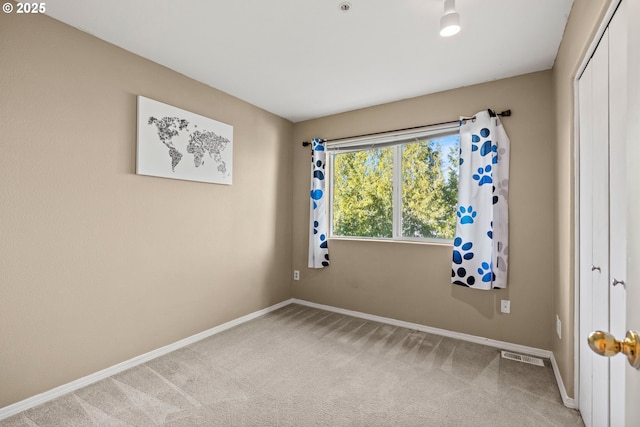 carpeted spare room featuring visible vents and baseboards