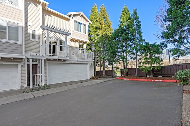 view of front facade with an attached garage, driveway, and fence