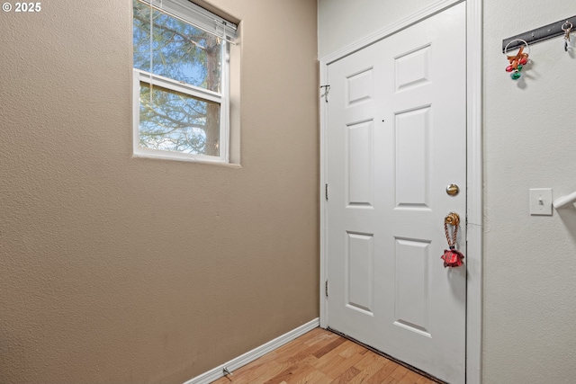 doorway to outside featuring baseboards and light wood-style floors