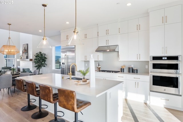 kitchen with white cabinetry, appliances with stainless steel finishes, and a kitchen island with sink