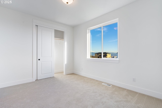 unfurnished bedroom featuring light colored carpet and a closet