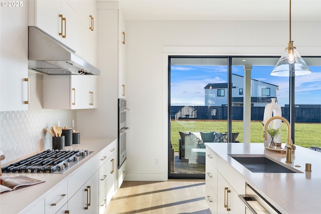 kitchen with pendant lighting, sink, decorative backsplash, and white cabinets