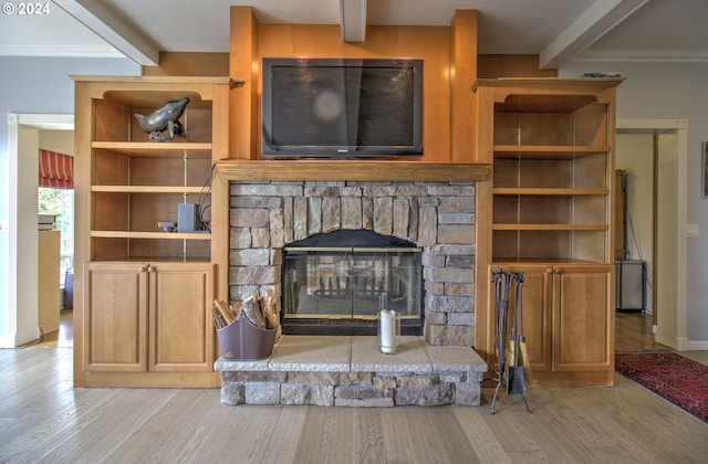 living room featuring beamed ceiling, a stone fireplace, ornamental molding, and light hardwood / wood-style flooring