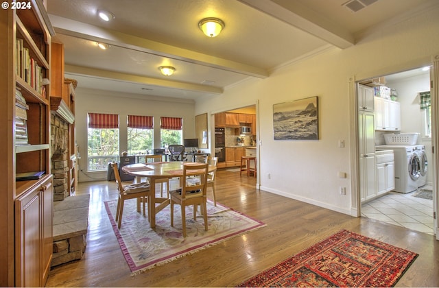 dining area featuring beam ceiling, washing machine and dryer, and light wood-type flooring